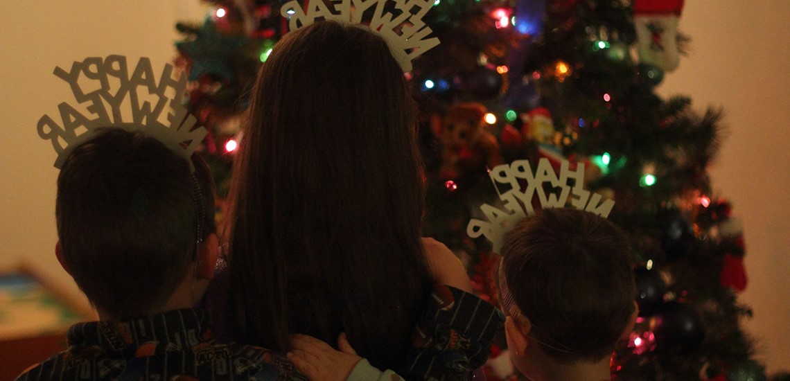 Photo of kids looking at a Christmas tree with Happy New Year hats