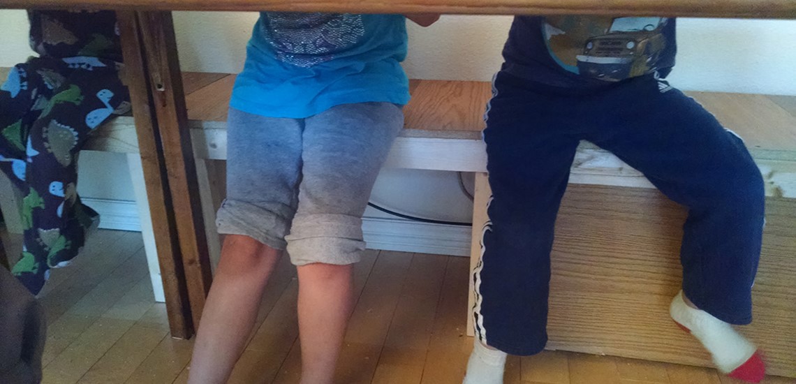 Photo of kids legs under a table