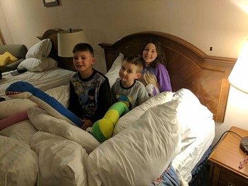 Kids siting on a hotel bed in pajamas