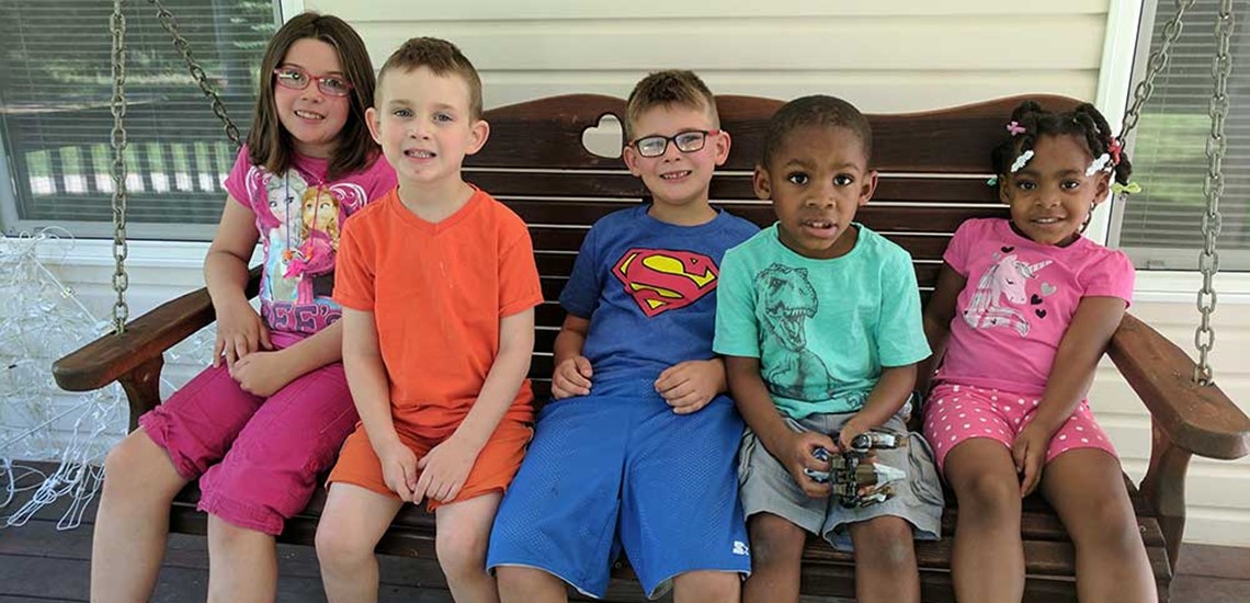 5 kids sitting on a park porch bench